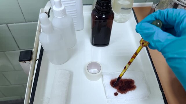 Doctor applying iodine solution with pipette onto gauze in dressing room