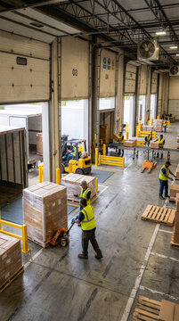 Warehouse workers loading cardboard boxes at busy commercial shipping dock during logistics operations