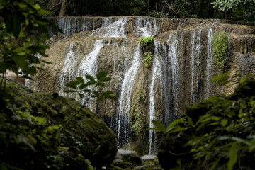 Scenic view of Erawan waterfall cascading down mossy rocks in dense green rainforest Kanchanaburi Thailand © VaZu Photo