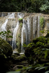 Powerful cascade of Erawan waterfall flowing down limestone cliff surrounded by tropical jungle Kanchanaburi Thailand © VaZu Photo