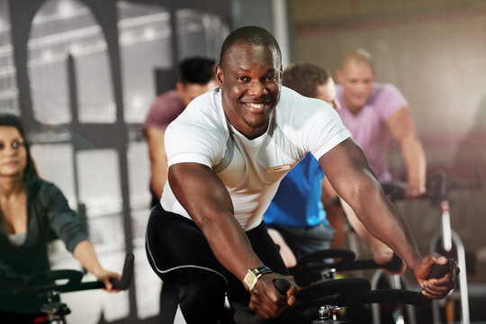Portrait, spin class or man on cycling bike in training or exercise for wellness, health or fitness. Athlete, smile or active people on bicycle machine for workout, body or challenge in gym community