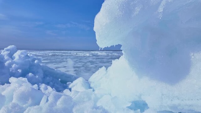 Big pieces of broken and melting ice with snow formed by winter freezing and lake storm. Ice melting heat dome phenomenon trapping and pressing hot air down. Climate change and extreme weather.