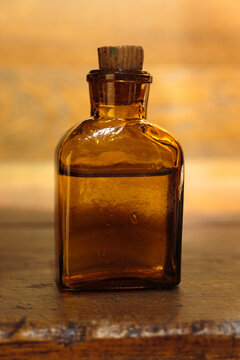 Amber glass bottle with cork stopper on rustic wooden surface. Apothecary, wellness, vintage product concept