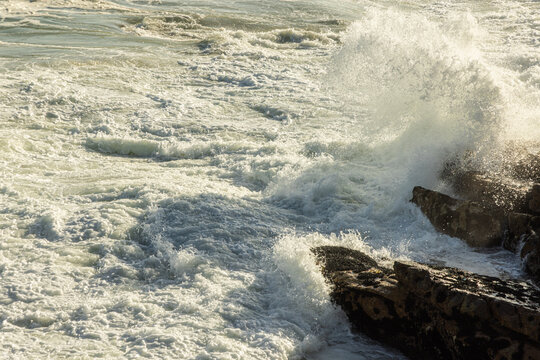large pounding waves and spray hitting rocky cliffs of Hermanus South African coastline