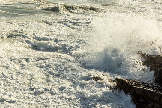 large pounding waves and spray hitting rocky cliffs of Hermanus South African coastline