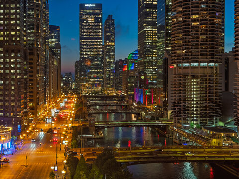 CHICAGO, IL, JUN 17, 2026: Night view from a high vantage showing the river bend, Marina City towers, Salesforce Tower, a thin crescent moon above, and amber-lit streets along the water