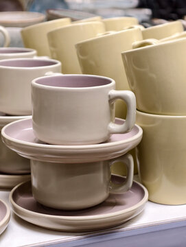 Ceramic cups paired with saucers arranged on store shelves showing a basic tableware collection intended for daily kitchen use and functional home serving needs