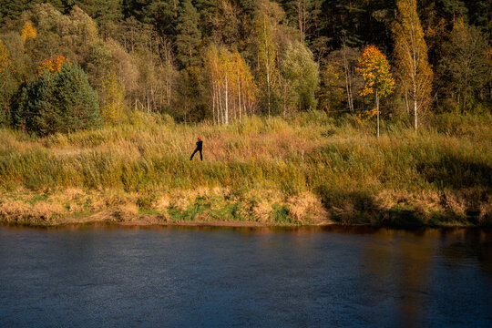 Person Riding a Zipline Above Riverbank in Colorful Autumn Landscape