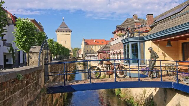 A scenic footbridge with a vintage motorcycle over the river in the historic center of Valkenburg, The Netherlands.