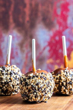 Caramel apples with peanuts and chocolate chips on a wood plate 