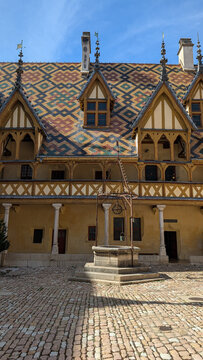 Historic well and colorful tiled roof at the Hospices de Beaune in France. 