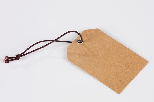 Blank brown cardboard tag with dark string attached on a white background