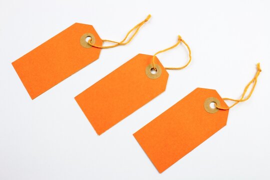 Three identical orange price tags with string gift tags yellow string