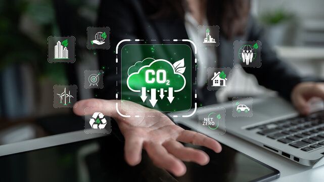 Person in business attire presenting CO2 reduction icons with green technology overlay emphasizing sustainability and environmental responsibility in a modern office setting Sigmoid