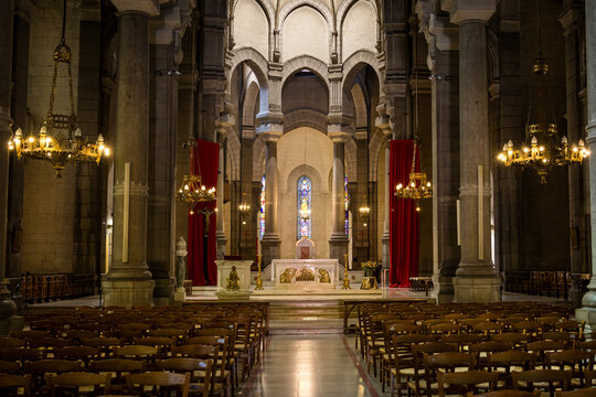 Grand nave interior of Cathedrale Saint Charles Borromee reveals gothic columns and golden chandeliers. Historic French church architecture concept highlights spiritual heritage in Saint Etienne.
