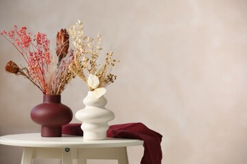 Naklejka premium Beautiful dried plants in vases on table against beige background. Space for text