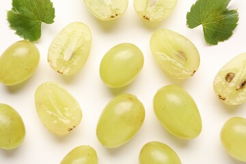 Naklejka premium Fresh ripe grapes and green leaves on white background, flat lay