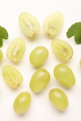 Naklejka premium Fresh ripe grapes and green leaves on white background, flat lay