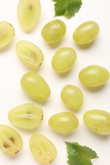 Naklejka premium Fresh ripe grapes and green leaves on white background, flat lay