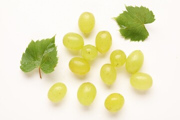 Fototapeta premium Fresh ripe grapes and green leaves on white background, flat lay