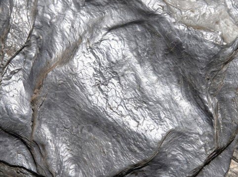 Raw rough shiny metallic graphite mineral stone surface texture close-up
