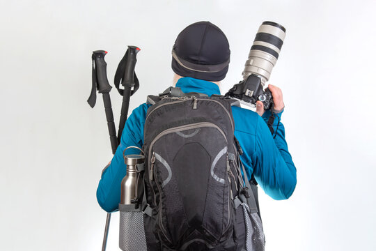 Hiker prepares for outdoor adventure with gear and camera in a bright setting