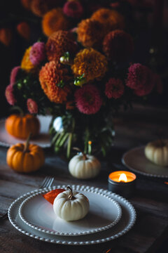 Fall table decoration with pumpkin composition. Family cozy thanksgiving dinner arrangement indoors, elegant wedding decor. Countryside style, candle light, autumn mood. Dark background