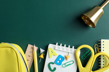 Different school stationery and bell on blackboard, flat lay. Space for text © New Africa