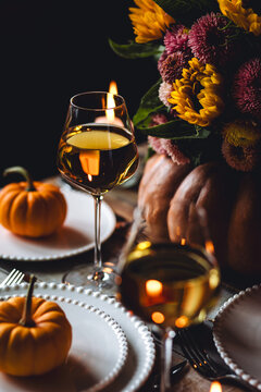 Idea for handmade elegant DIY atmospheric dinner table setting for thanksgiving family dinner or wedding celebration. Fall romantic cozy home atmosphere. Wine, floral pumpkin centrepiece, sunflowers