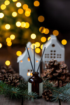 Aroma burning candles, aromatic reed diffuser in glass bottle. Cozy Christmas atmosphere at home. Holiday scent, aromatherapy. Fir tree fragrance, spruce, cedar, winter mood, knitted sweater