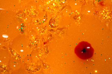 Abstract amber liquid texture with golden glitter and a striking red droplet – Metaphor for contrast, precision, and passion © alaa