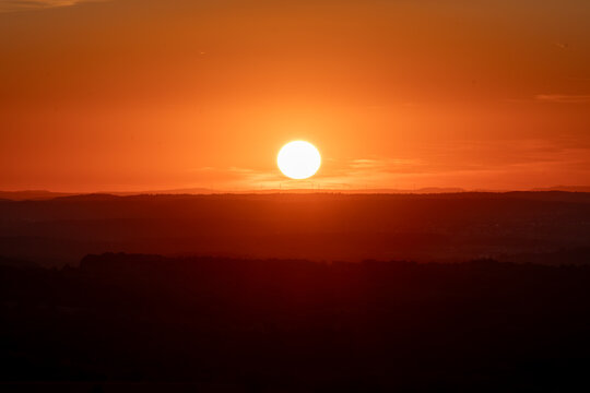 Vibrant Orange Sunset Over Silhouetted Landscape