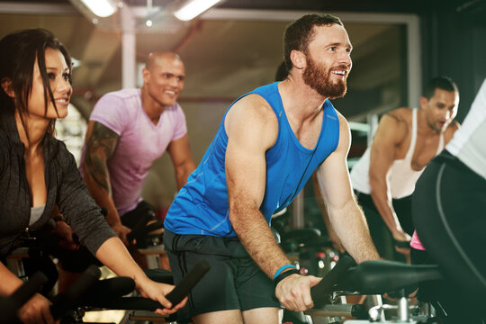 Happy, spin class or man on cycling equipment in training exercise for wellness, health or fitness. Athlete, challenge or active people on bicycle machine for workout, body or cardio in gym community
