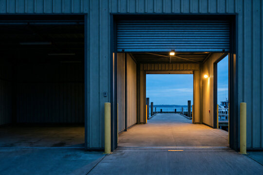 Industrial warehouse loading dock open to a boat pier at dusk