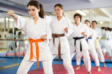 Group of women in kimonos train karate techniques in studio © JackF