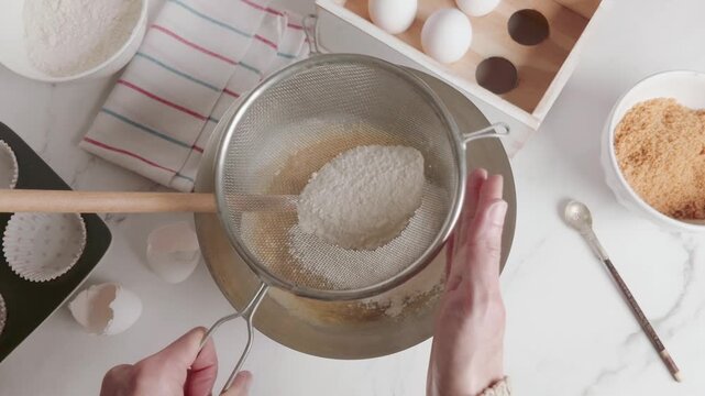 Hands of a woman sifting flour through a strainer. Horizontal format. 