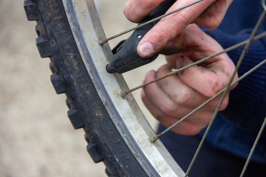 Close-up of hands repairing and truing bicycle wheel spokes