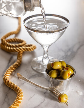 Martini being poured with olives on the side