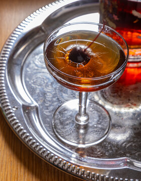 Manhattan with cherry splash on silver tray
