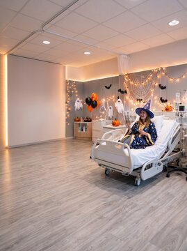 Hospital patient wearing a magician costume during a festive Halloween celebration in a decorated medical room