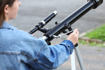 Fototapeta premium Astronomy and science education, young woman using a telescope for stargazing and space exploration in an outdoor setting with curiosity and focus