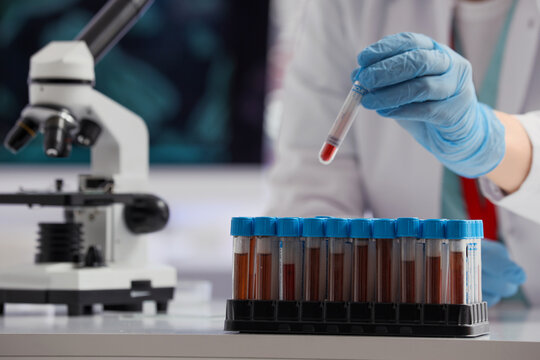 Medical diagnostics and blood testing, scientist holding a test tube with sample in a clinical laboratory for pathology research and disease screening