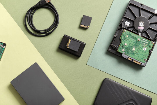 Data storage and digital security, computer hardware components with hard drives and memory cards on a geometric green background for technology concepts