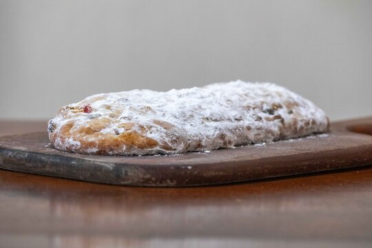 Christstollen, traditional German Christmas fruit bread dusted with powdered sugar and cut into slices, showing the dense crumb studded with candied cherries, candied fruit, raisins and nuts.