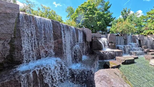 camera rises beside cascading water to show the landscaped Washington memorial fountain.
