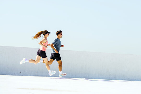 Couple enjoys a vibrant morning run on a bright rooftop under a clear sky