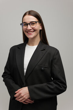 Professional woman in a sleek black suit smiles confidently against a neutral background