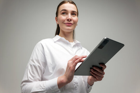 Woman using tablet while smiling in a bright studio setting