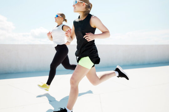 Two friends jogging under a bright blue sky on a sunny day, enjoying their outdoor exercise routine