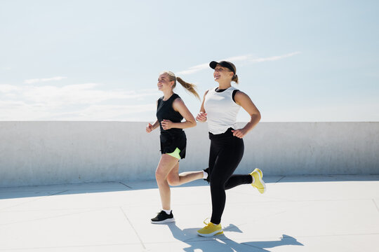 Friends jogging joyfully under a clear blue sky on a bright sunny day